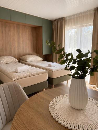 a room with two beds and a table with a vase at Szarotka Łeba - nowe domki blisko plaży in Łeba