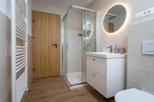 a bathroom with a shower and a sink and a mirror at Start Point Apartments in Žirovnica