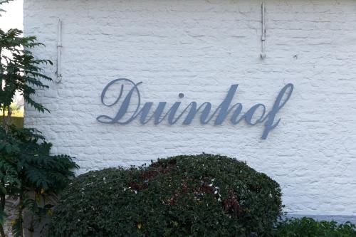 a sign on the side of a white brick building at Country House Duinhof in De Haan