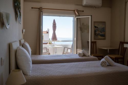 a hotel room with two beds and a view of the ocean at Pelagia Beach Studios in Agia Pelagia