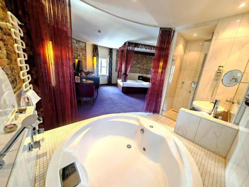 a large bathroom with a tub and a bedroom at Hotel Öhlknechthof in Horn