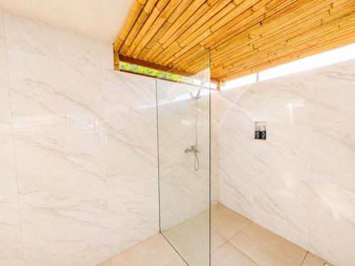 a bathroom with a shower with a glass door at SūKha Amed in Culik