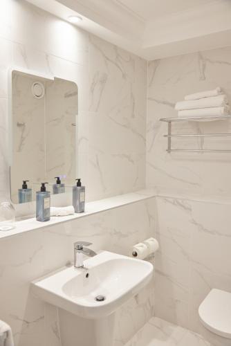 a white bathroom with a sink and a mirror at Bunratty Castle Hotel & Leisure Club, BW Premier Collection in Bunratty