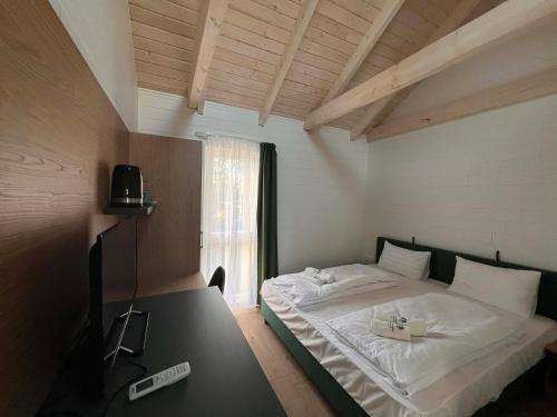 a bedroom with a bed with a table and a window at Zánka Vízparti Üdülő in Zánka