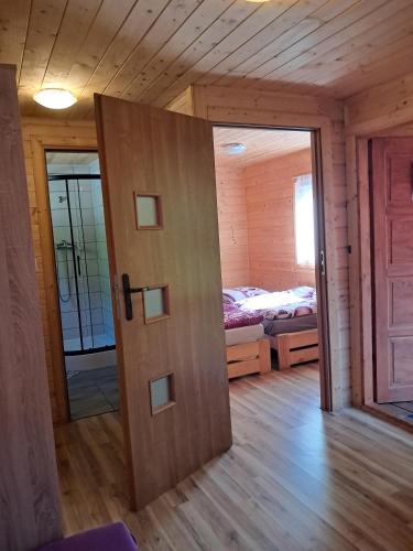 a door to a room with a bed and a bedroom at Domki Mucki in Międzywodzie