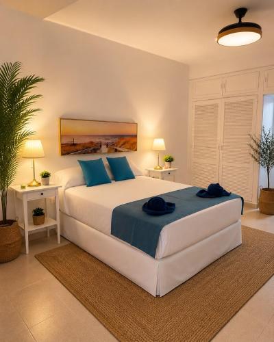 a bedroom with a large white bed with blue pillows at Sea View Colony Club in Puerto del Carmen