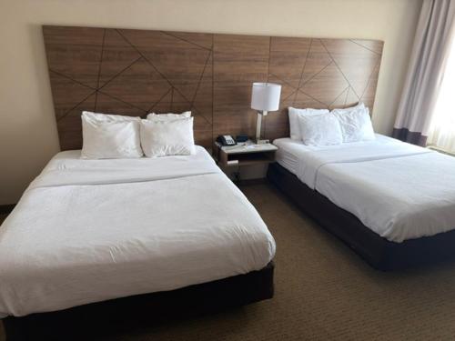 a hotel room with two beds and a head board at Wingate by Wyndham Utica in Utica