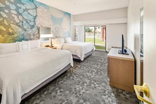 a hotel room with two beds and a flat screen tv at Courtyard by Marriott Bryan College Station in College Station