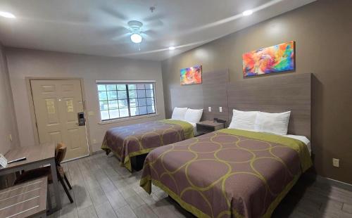 a hotel room with two beds and a desk at Lone Star Inn - San Benito Los Indios in San Benito