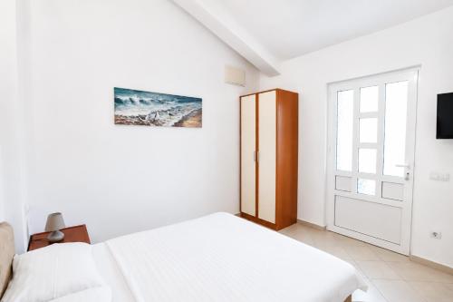 a white bedroom with a bed and a sliding door at Apartments Sofia in Sutomore
