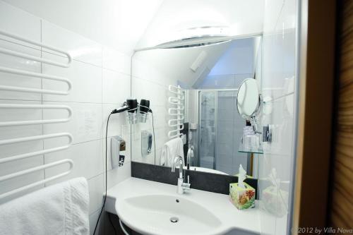 La salle de bains blanche est pourvue d'un lavabo et d'un miroir. dans l'établissement Villa Nova - Hotel garni, à Waidhofen an der Ybbs