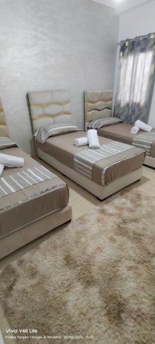 two beds in a bedroom with a rug at Appartement à louer wadie in Fnidek