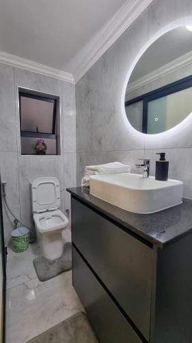 a bathroom with a sink and a toilet and a mirror at Luxury Fairland Fully Serviced Cottages in Johannesburg