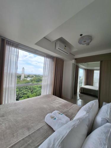 a bedroom with a large bed with a large window at De Luxe, Standard and Studio Suites -The Breeze Residences-close to Airport,Mall of Asia, US Embassy in Manila