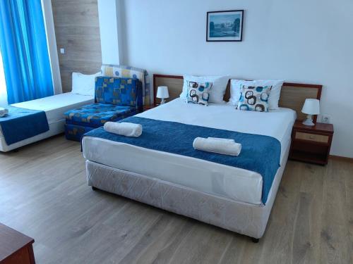 a bedroom with a large bed and a chair at Albatros 2 Family Hotel in Kiten