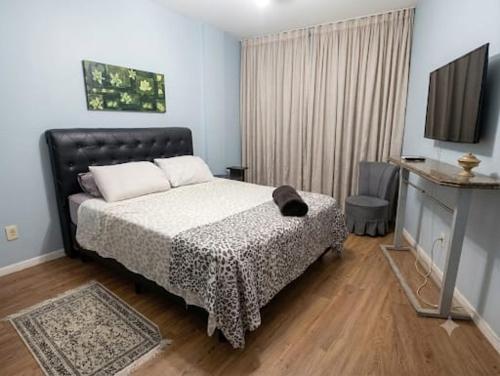 ein Schlafzimmer mit Bett und Flachbildfernseher in der Unterkunft Apartamento Gonzaga Santos in Santos