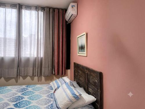 a bedroom with pink walls and a bed and a window at Apto Gonzaga a 20m da praia -Ar Split & Pet Friendly in Santos
