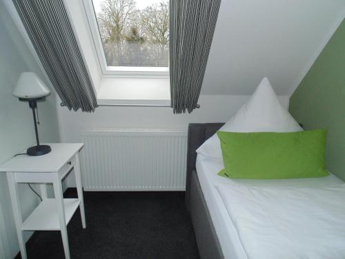 a bedroom with a bed with a green pillow and a window at Landhaus Elbeflair bei Dömitz in Lenzerwische