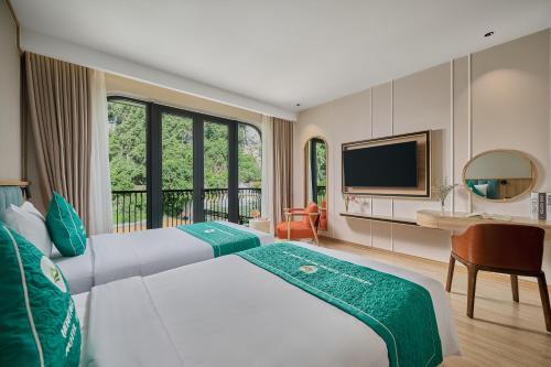 a hotel room with a large bed and a television at Heritage Charm Hotel Trang An in Ninh Binh