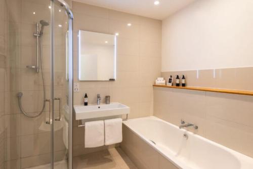 a bathroom with a tub and a sink and a shower at St Enodoc Hotel by Paul Ainsworth in Wadebridge