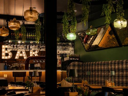 a restaurant with a bar with tables and lights at Hotel Evo in Witunia