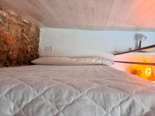 a bedroom with a white bed with a stone wall at Alojamiento Colinas in Monachil