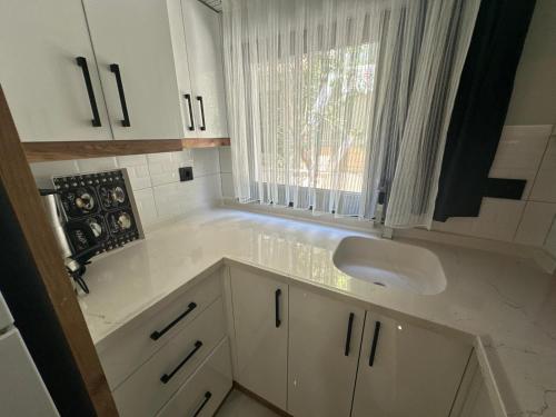 a white kitchen with a sink and a window at Benan Apart Otel Didim in Didim