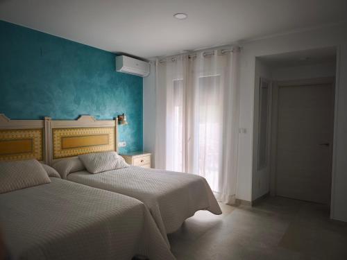 a bedroom with two beds and a blue wall at PARAISO PLAYA Hotel in Isla Cristina