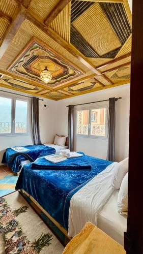 two beds in a bedroom with a coffered ceiling at Hotel New Mars Dades in Aït Idaïr