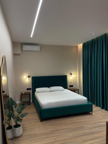 a bedroom with a large bed with green curtains at Olivium Rooms in Vlorë
