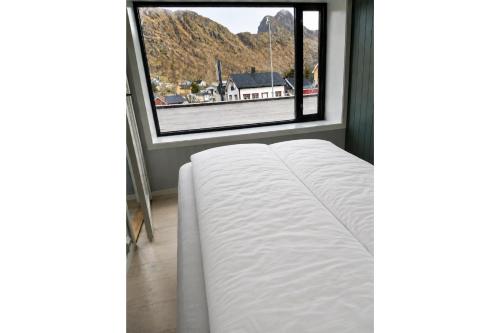 a bed in a room with a large window at LofotenApartmentOne in Stamsund