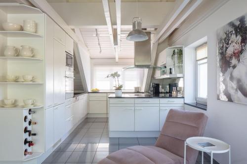 a kitchen with white cabinets and a pink chair at Ferienwohnung Blaupause Reichenau mit Seezugang und Wiese zum Entspannen in Reichenau