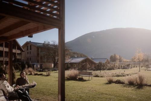 two people sitting on a porch with a mountain in the background at Kessler's Mountain Lodge in Natz-Schabs