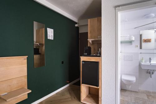 a green bathroom with a toilet and a sink at DuinHotel Texel in De Koog