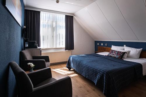 a hotel room with a bed and a chair at DuinHotel Texel in De Koog
