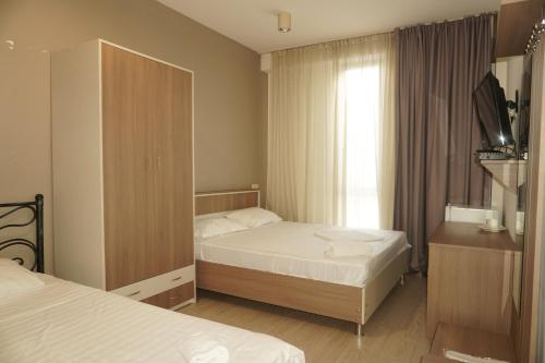 a small bedroom with two beds and a television at Hotel PM Palace in Nizhnyaya Alekseyevka