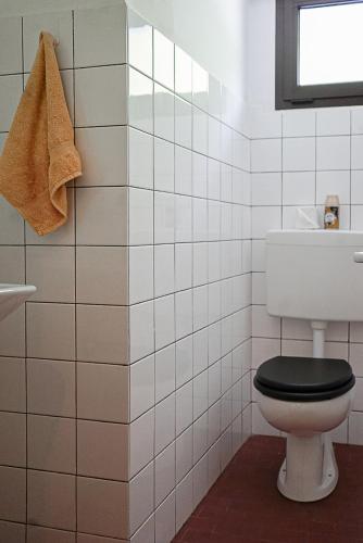 a white tiled bathroom with a toilet and a window at Ristorante Locanda Zott in Valle Onsernone in Vergeletto