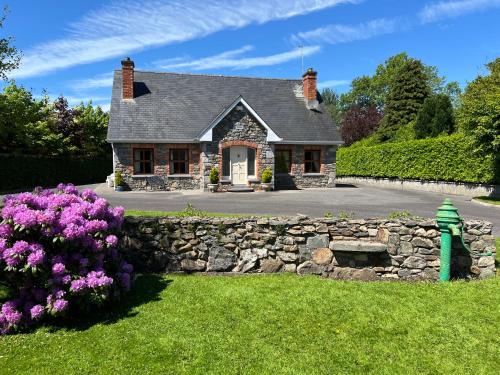 a stone house with a stone wall and purple flowers at Laurel Lodge in Virginia