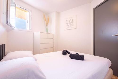 a white bedroom with two beds and a window at Valras-Loc - T2 Piscine Terrasse in Valras-Plage