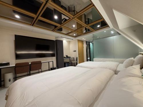 a bedroom with two beds and a flat screen tv at 잠실 라운지 호텔 in Seoul
