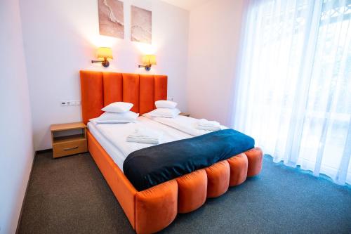a bed with an orange headboard in a room at Vila Aura in Sovata