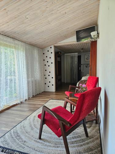 a room with red chairs and a table and a bed at Namiņš AMRAI in Ventspils