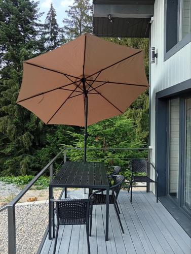 a table with an umbrella on a porch at Перлина Гір in Yablunytsya