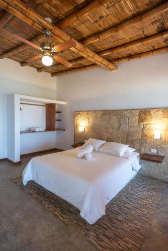 a bedroom with a white bed with a stone wall at El Mirador de Vichayito in Vichayito