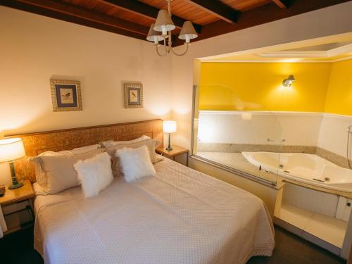 a bedroom with a large bed and a bath tub at Lê Château Hotel de Gramado, seu refúgio no centro da cidade in Gramado