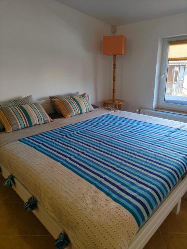a large bed with a blue striped blanket on it at Studio dwupokojowe z łazienką i kuchnią in Augustów