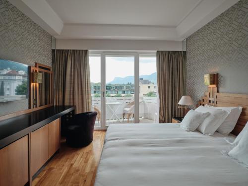 ein Hotelzimmer mit einem großen Bett und einem Balkon in der Unterkunft Hotel Aurora in Meran