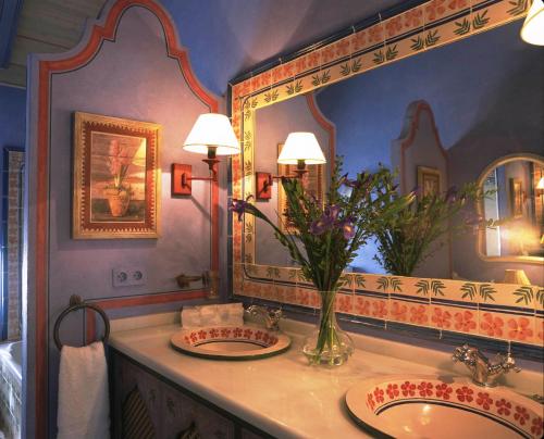 a bathroom with two sinks and a vase of flowers at Hacienda de Orán in Utrera