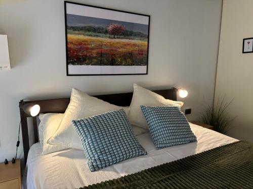 a bed with two pillows and a picture on the wall at Station -Mansarda in posizione strategica, vista panoramica, letto king size e clima in Ivrea