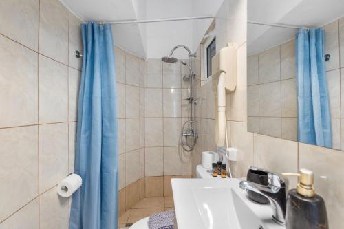 a bathroom with a blue shower curtain and a sink at Julies Studios in Chania